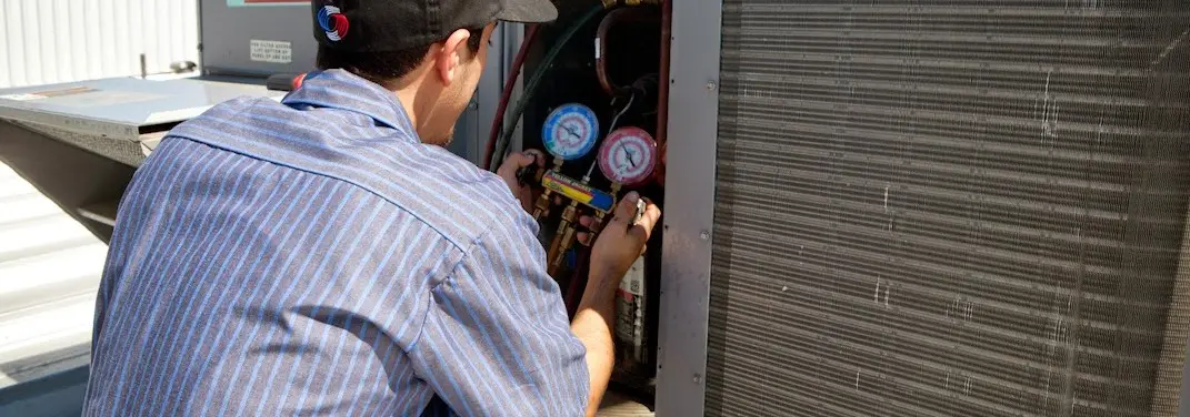 HVAC technician servicing a condenser unit in Duvall